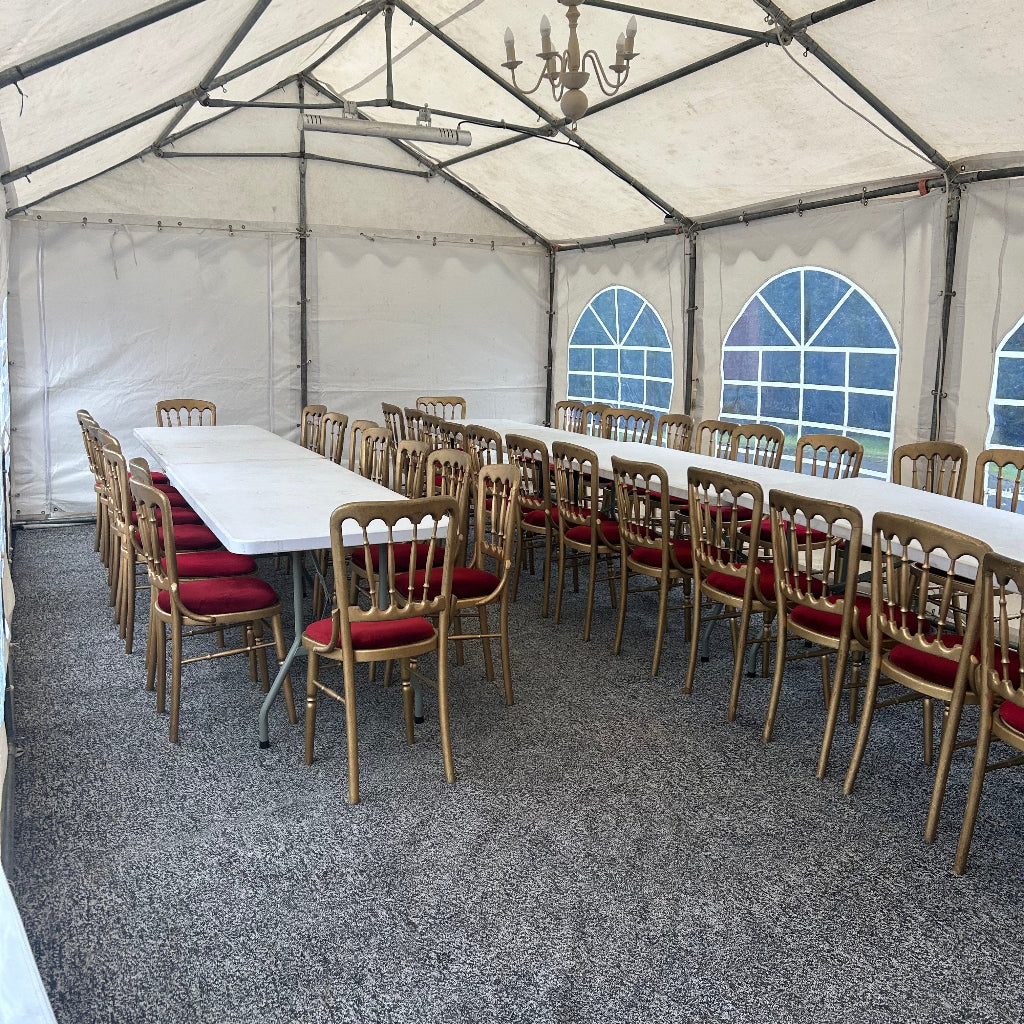 Row of chairs under a large white tent with blue window designs on the wall.