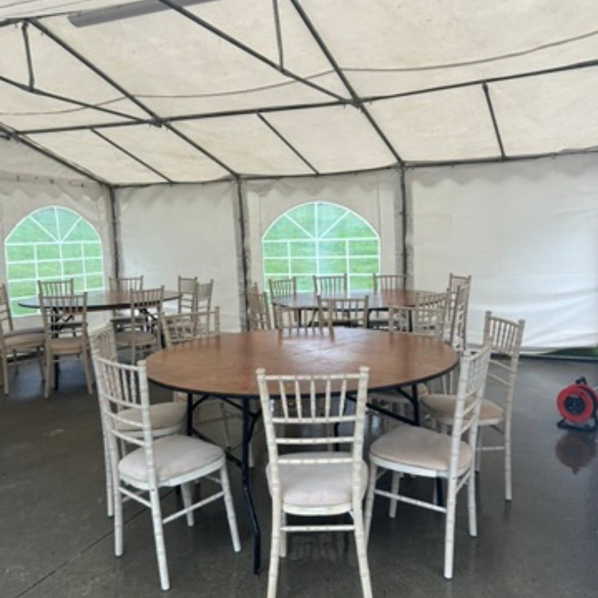 Tent interior with round tables and chairs set up for an event.