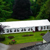 Large white tent on a grassy area surrounded by trees