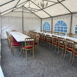 Row of chairs under a large white tent with blue window designs on the wall.