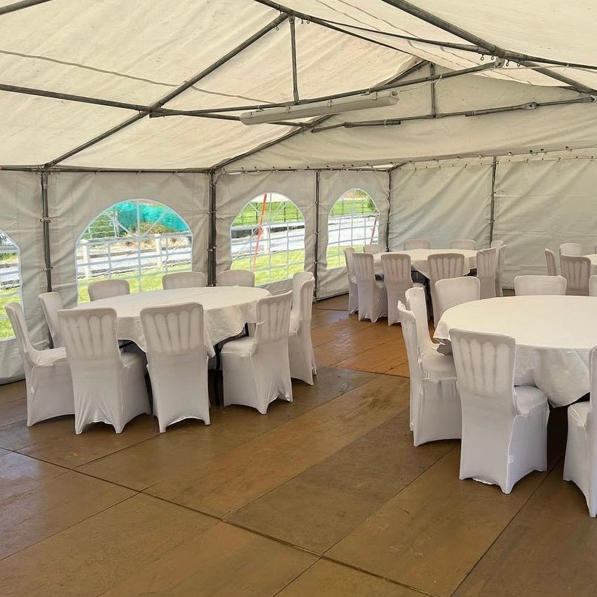 Event tent with white tables and chairs set up for an outdoor gathering.