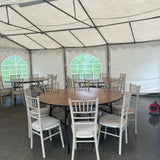 Tent interior with round tables and chairs set up for an event.