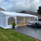 White 6x10 meter marquee tent set up outdoors with furniture and decor inside.