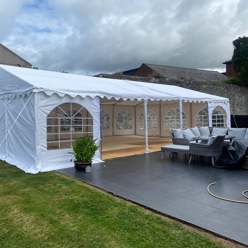 White 6x10 meter marquee tent set up outdoors with furniture and decor inside.