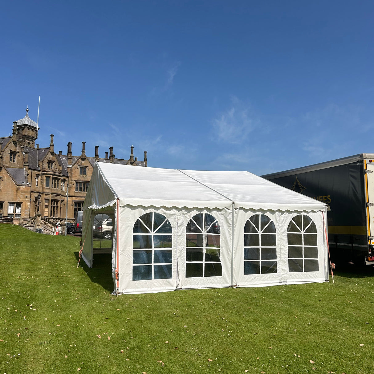 White marquee tent on grass with a clear blue sky
