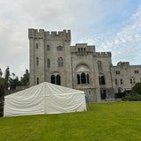 Castle-like building with a white tent in front on a grassy area