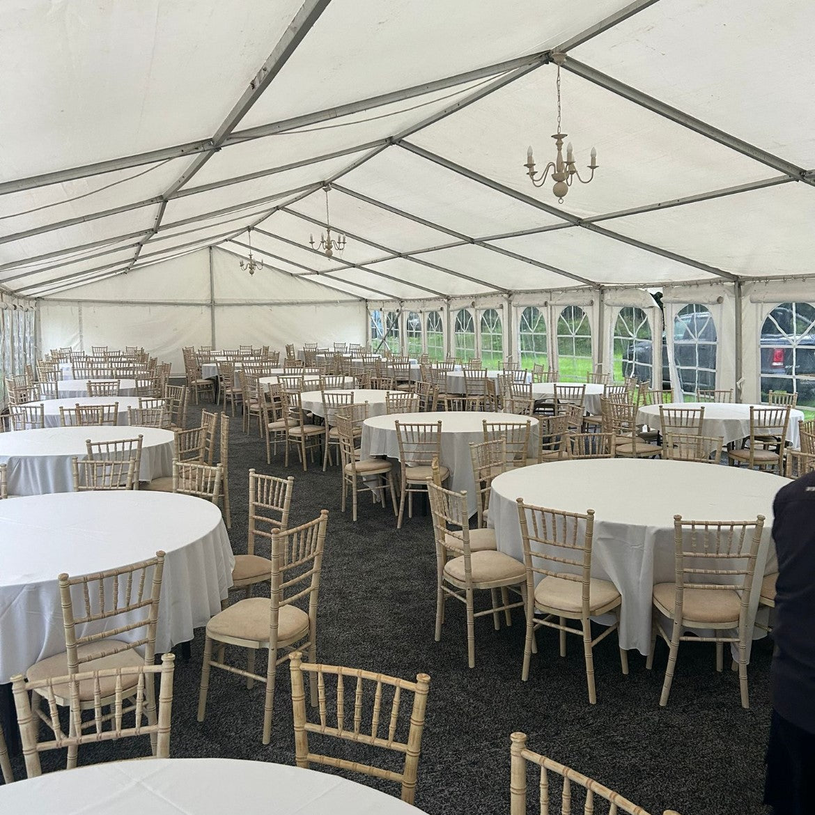 Large indoor event space with white tables and chairs under a white tent.