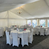 Event setup with white tables and chairs under a large white tent.