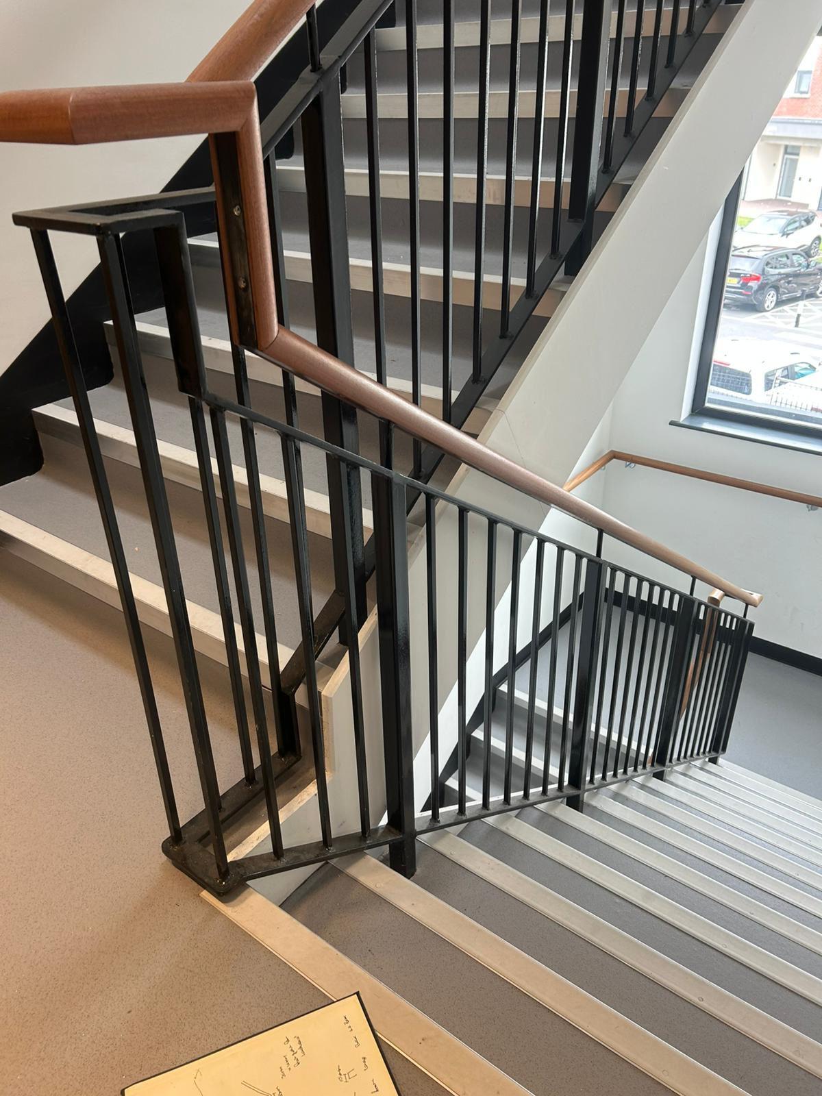 Staircase with black metal railing and wooden handrails in a modern interior setting.